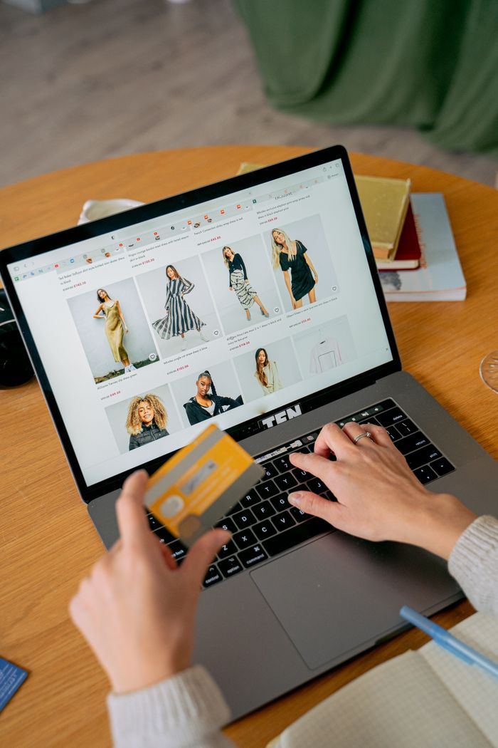 about-us A woman makes an online purchase using a credit card on her laptop, browsing an online fashion store.